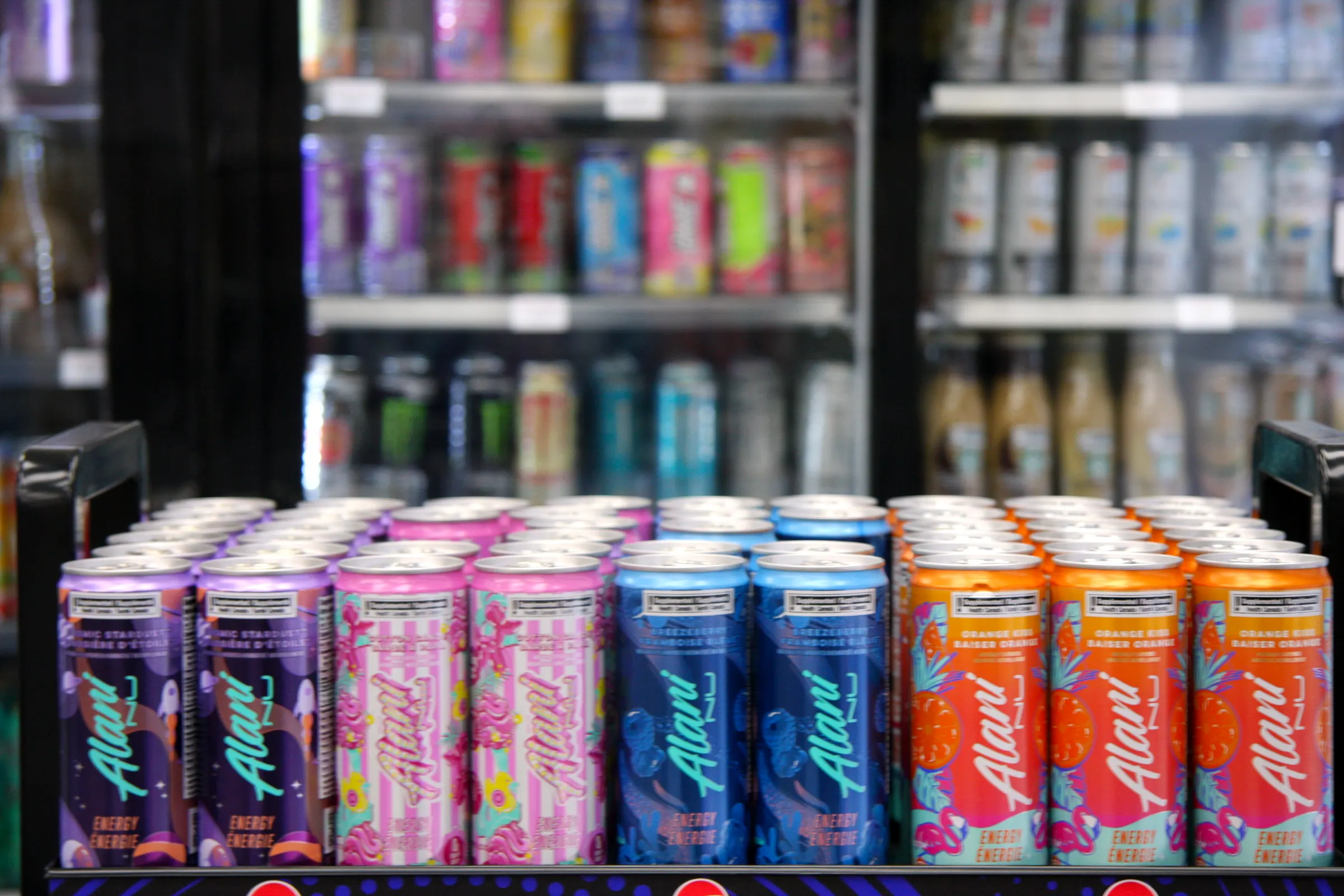 Close, shallow-focus row of energy drink cans, condensation and colour reading across the front face.