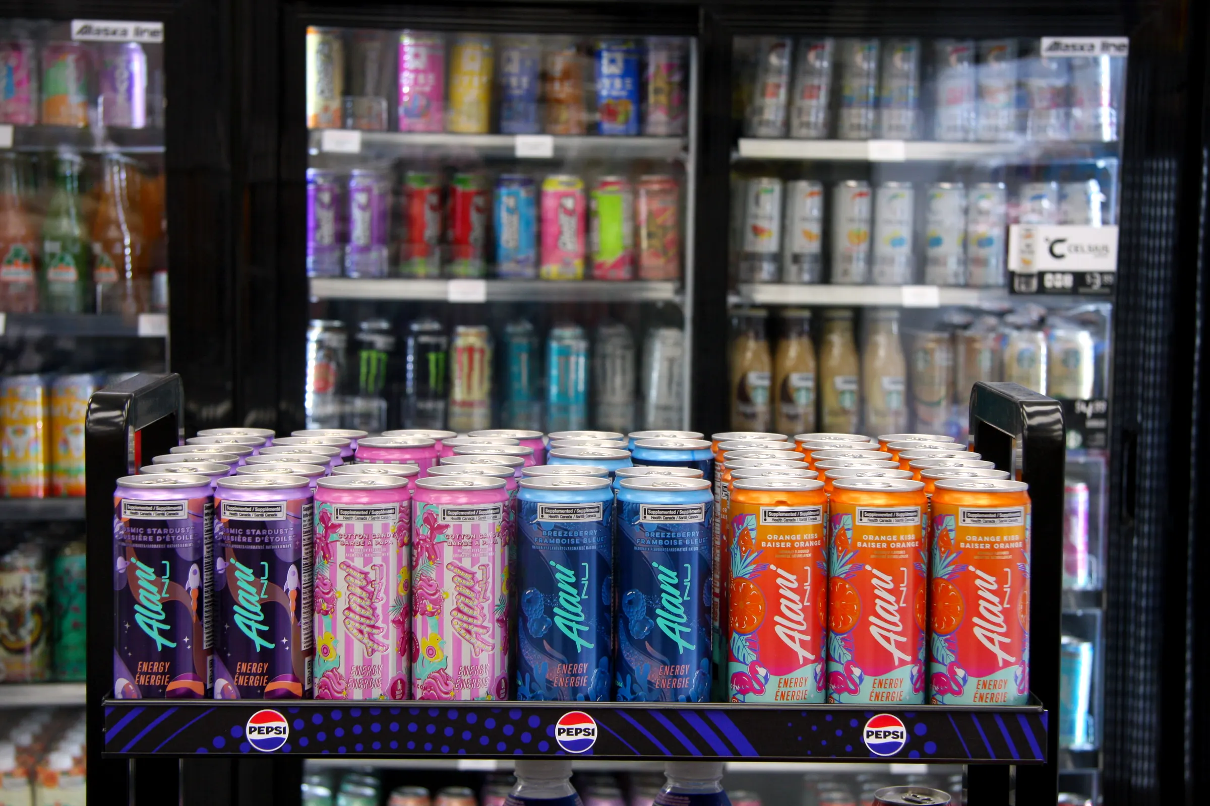The energy display against the full run of cooler doors, the cans ranked by flavour along the front edge.