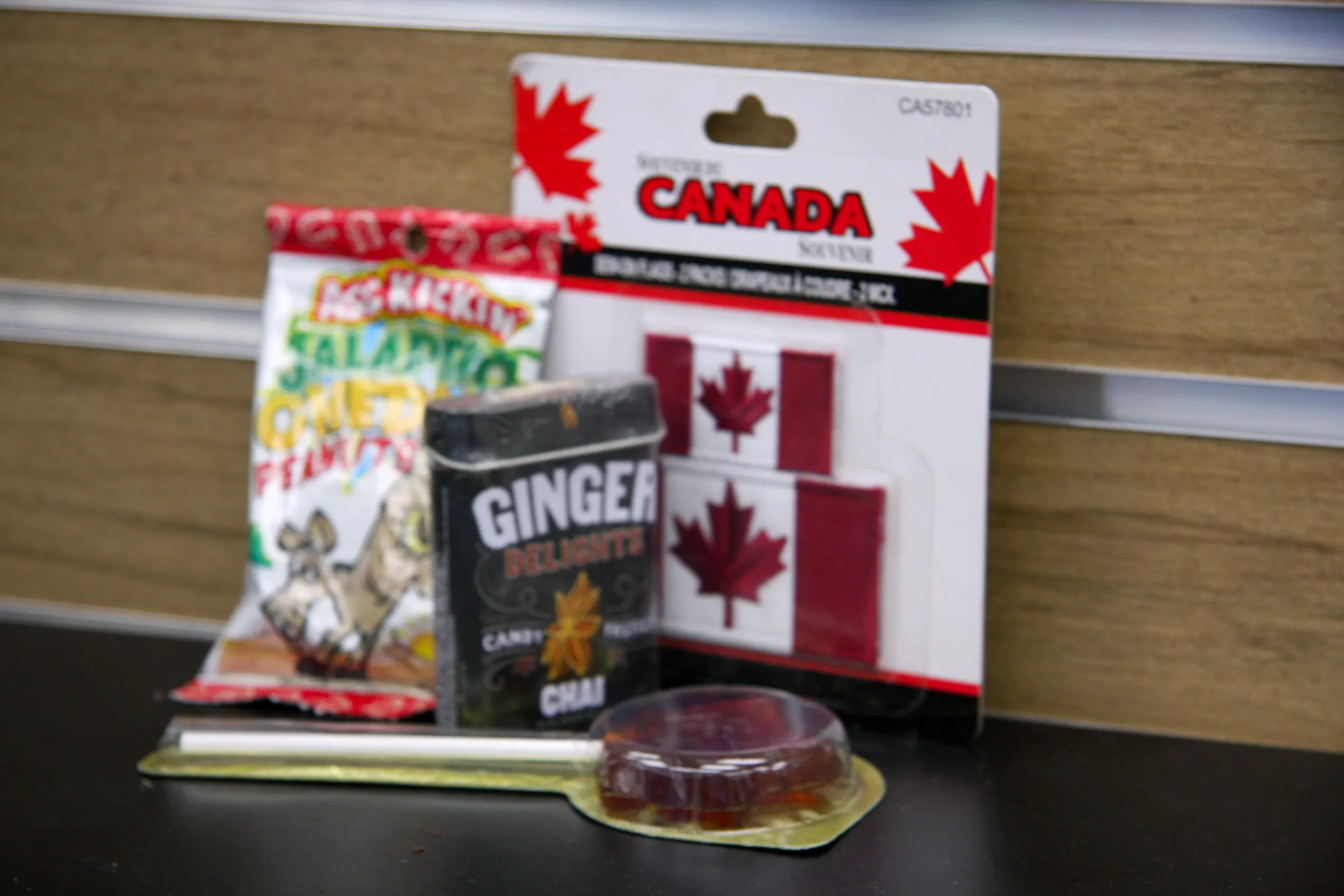 The Canada souvenir range on the counter — sew-on flags, spiced peanuts and a tin of ginger chai candy.