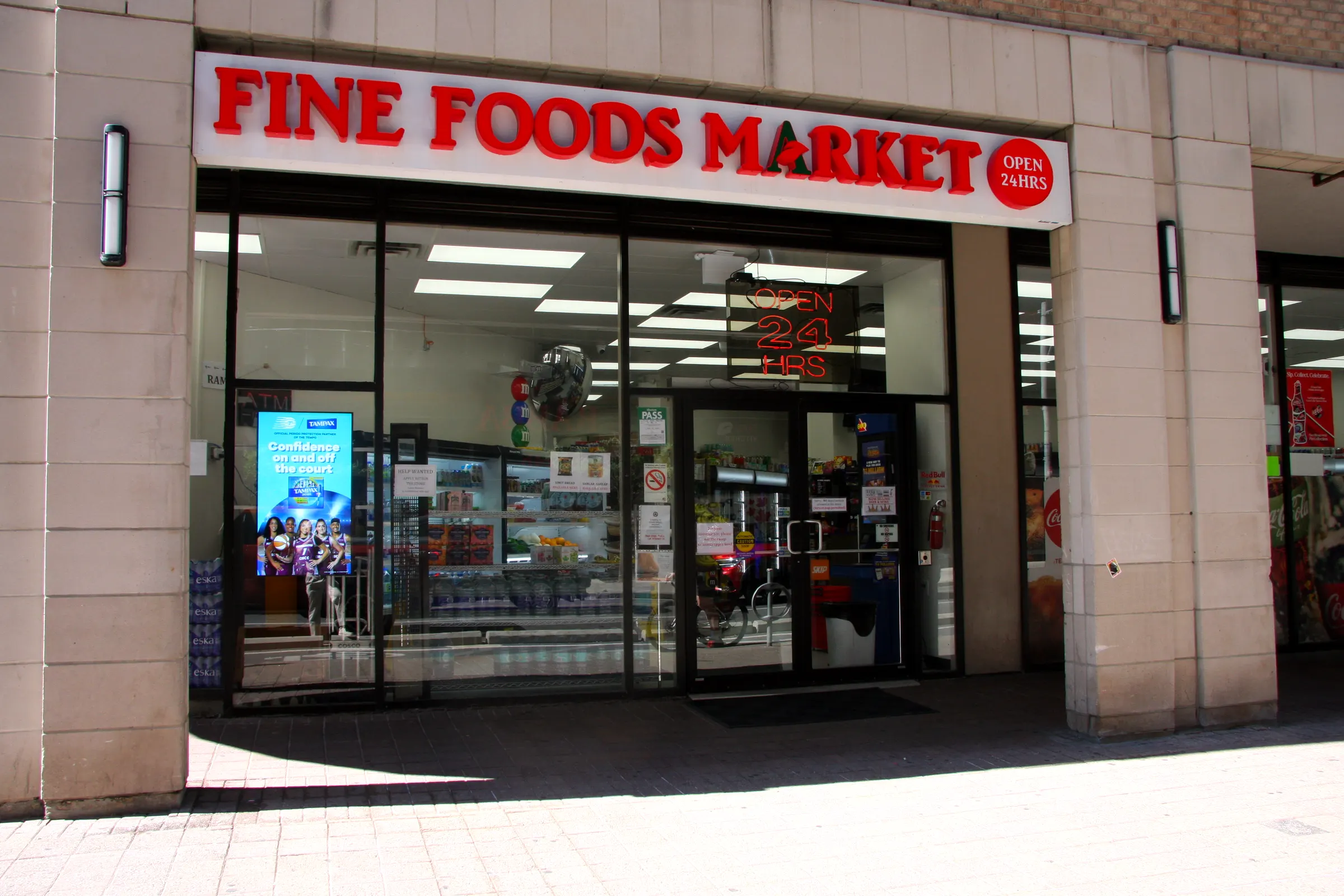 The Fine Foods Market storefront — red signage over glass doors, open 24 hours, on the concourse of a downtown Toronto office tower.